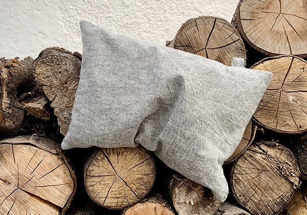 Zirbenkissen auf Holzscheiten – natürlicher Zirbenduft, handgemacht bei NATURKINDER